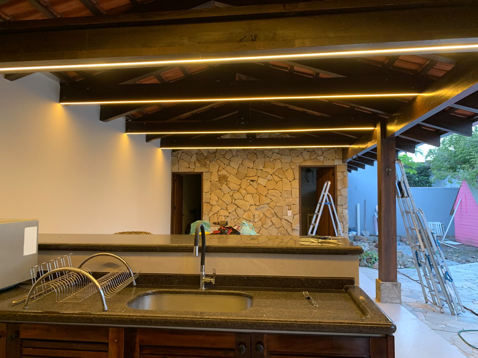 Área gourmet com fita de LED embutida nas vigas de madeira, instalada pela NAJ Elétrica