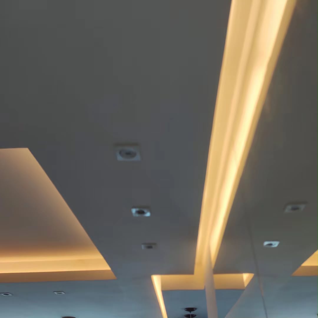 Teto com rasgos de LED e spots embutidos em ambiente residencial
